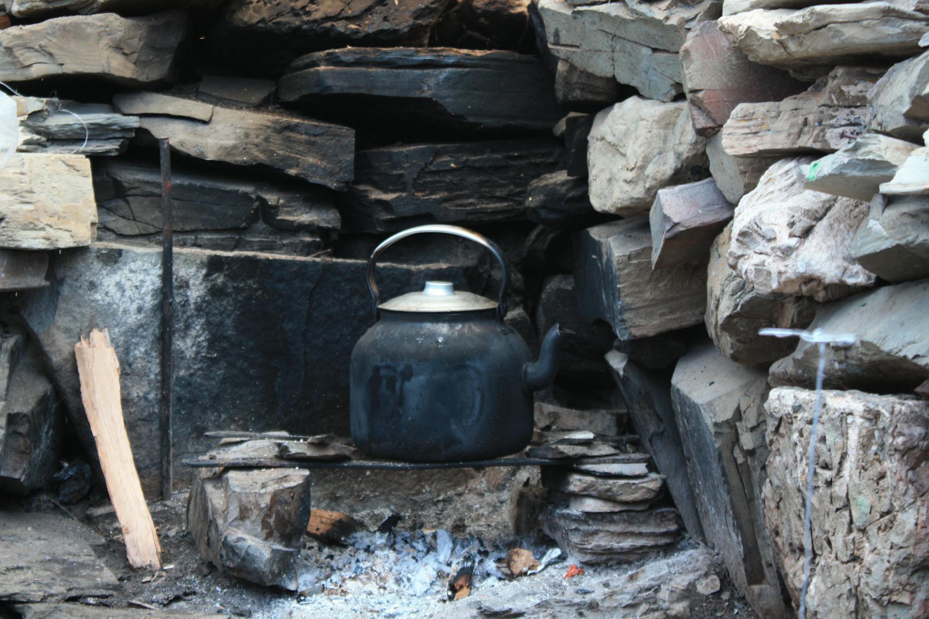 Metalowy czajnik na kamiennym kominku w przytulnym wnętrzu