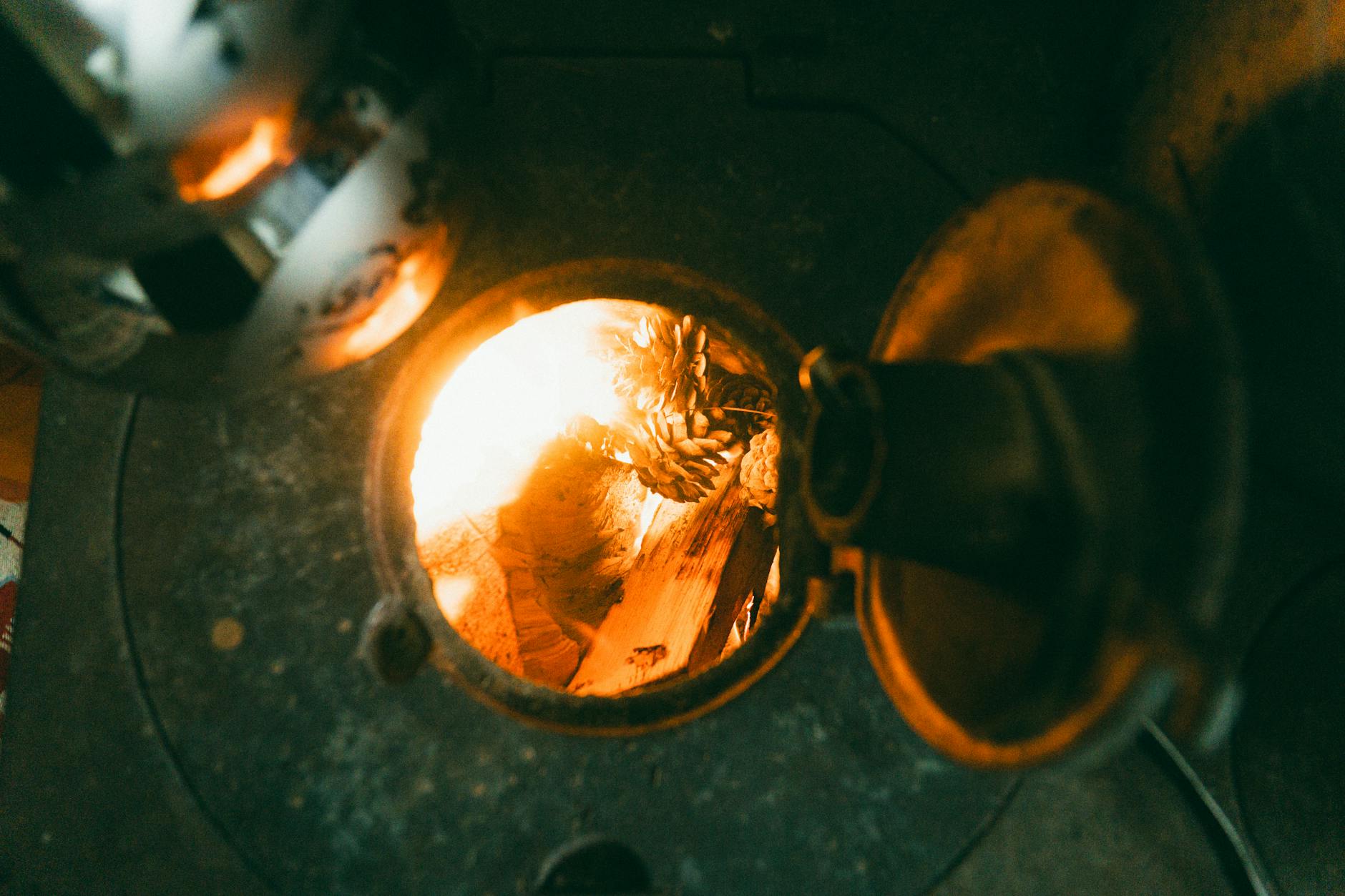 Płonące polana w żeliwnym piecu, ogień widoczny przez otwarte drzwiczki