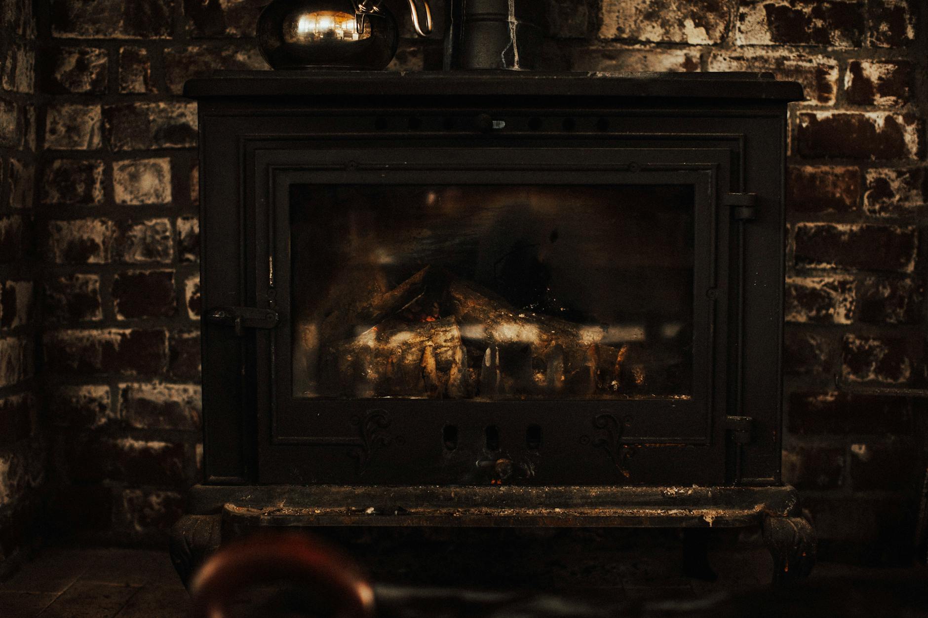 Rustykalny kominek na drewno w ceglanej ścianie