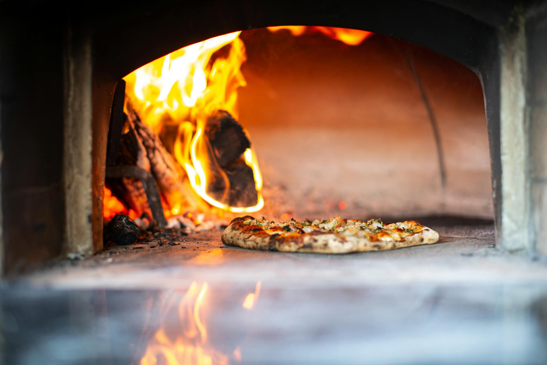 Pizza piecze się w murowanym piecu opalanym drewnem z widocznym ogniem