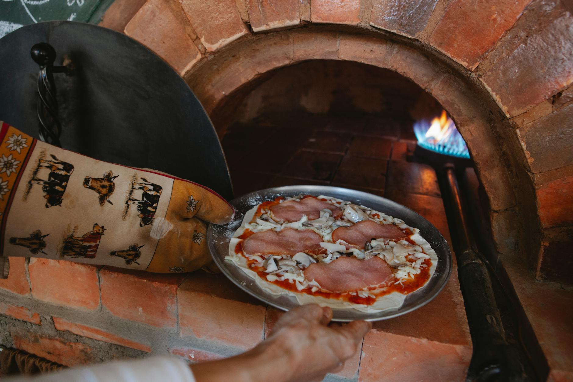 Pizza z szynką i serem w murowanym piecu opalanym drewnem