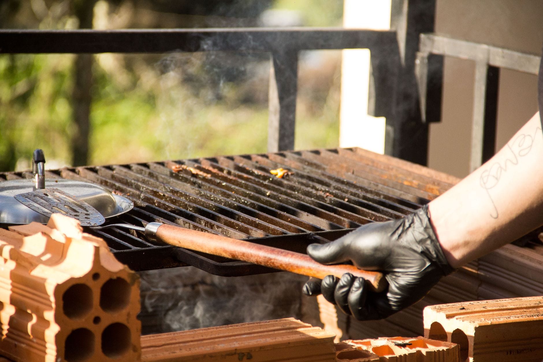 Grill murowany z daszkiem: ochrona przed deszczem bez problemów z dymem Ręka w rękawicy obraca mięso na rozgrzanym grillu w ogrodzie